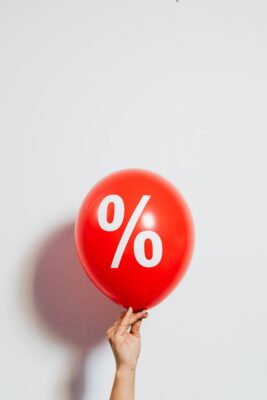 Hand holding a red balloon with a white percentage symbol.