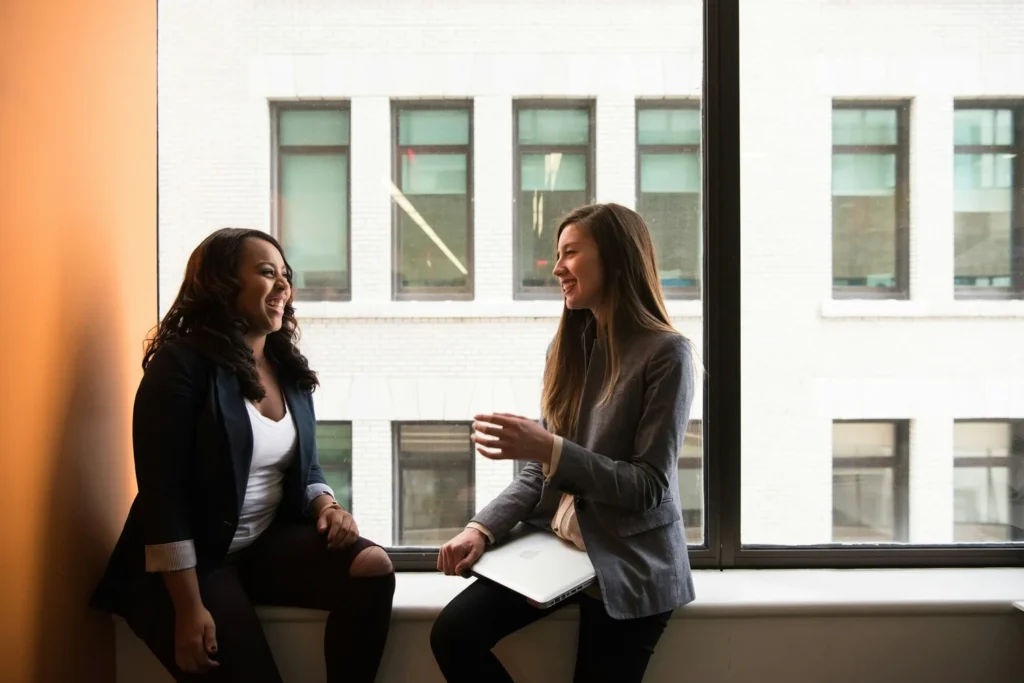 Two women in conversation beside an office window.