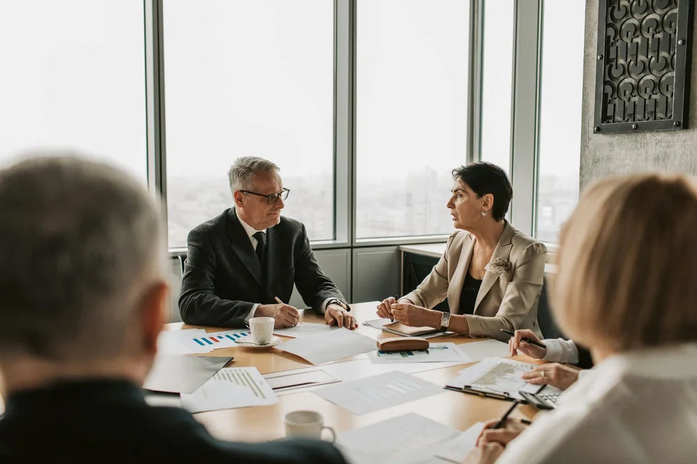 Four professionals reviewing charts and documents during a meeting.